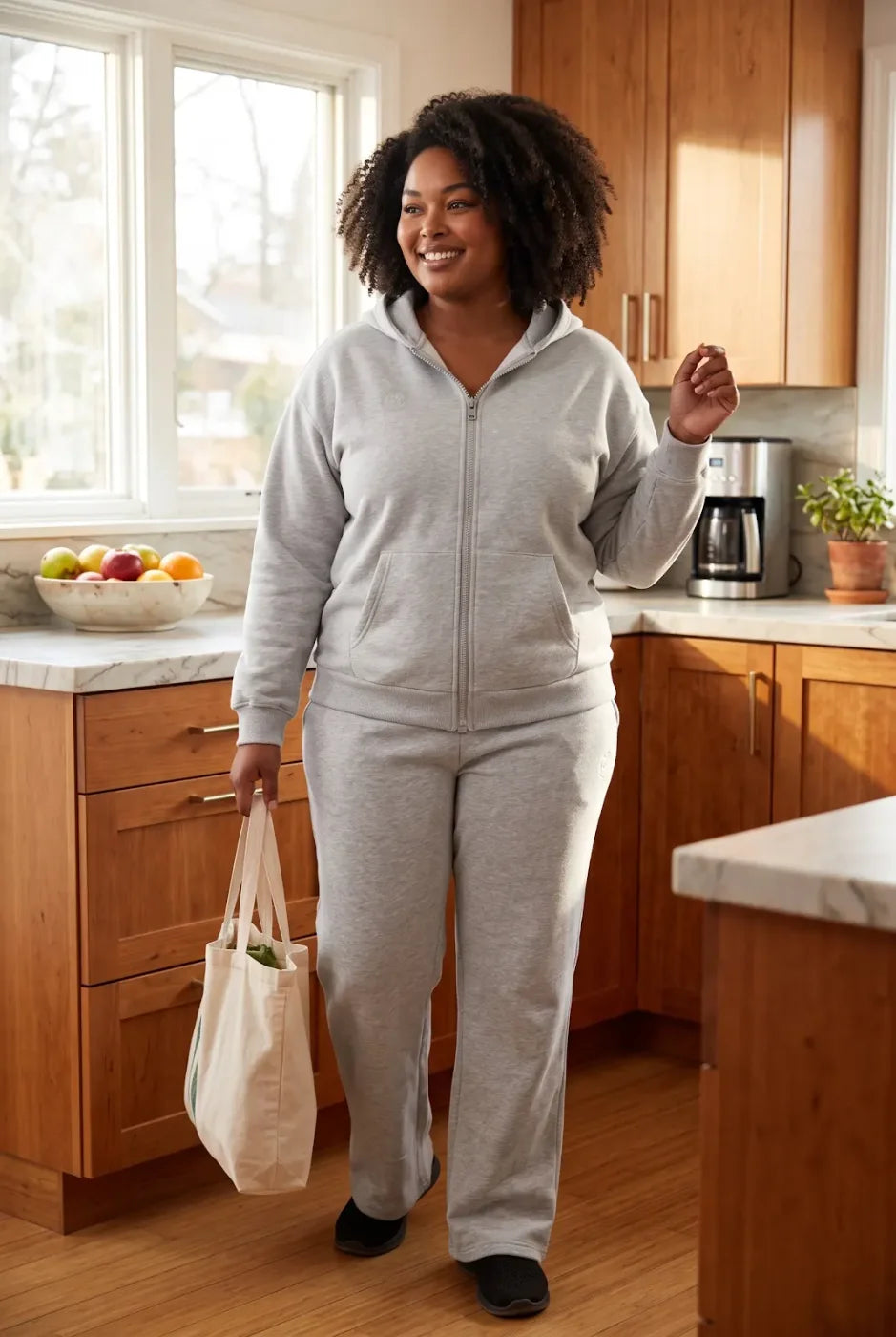 A woman in her kitchen in the gray FREEDOM Hoodie and Jogger