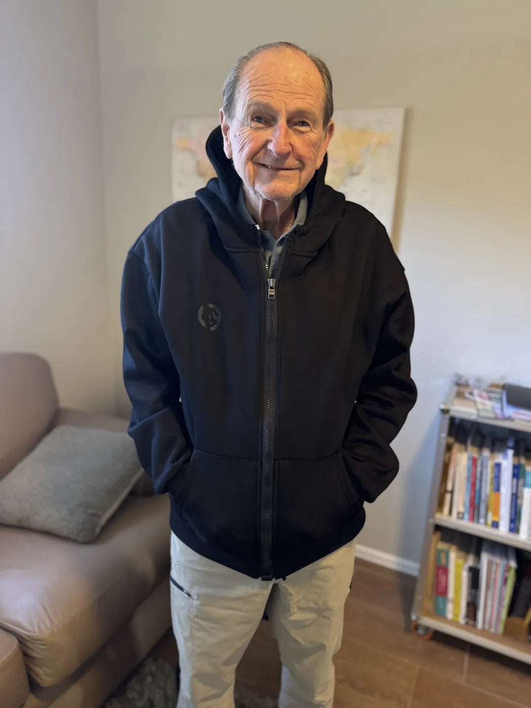An older man smiling in a black FREEDOM Hoodie at home