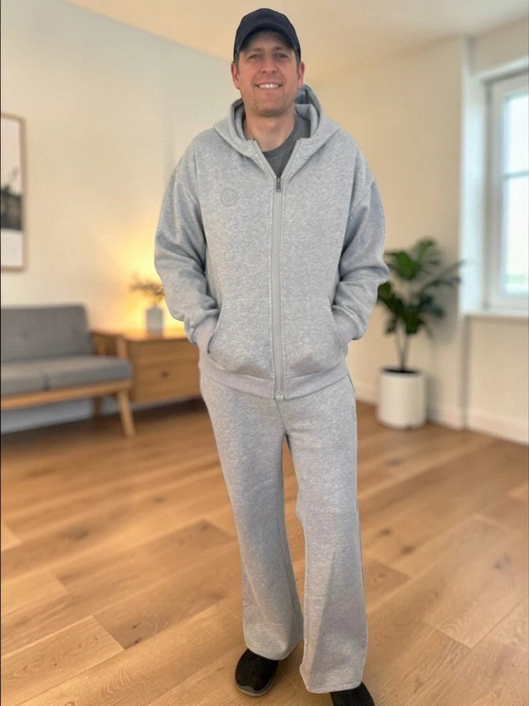 A man in the gray FREEDOM Hoodie and Jogger at home