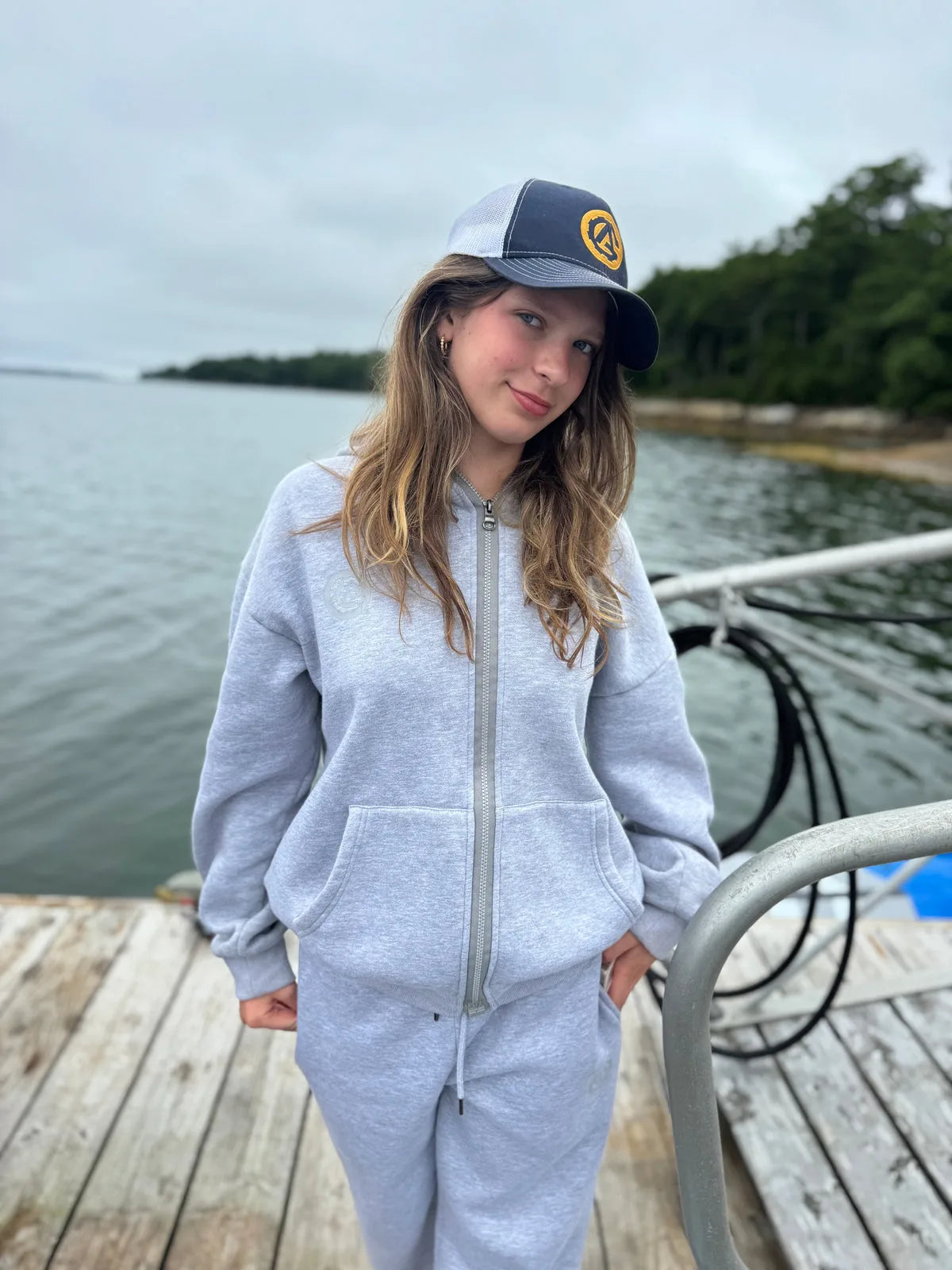 A girl in a gray FREEDOM Hoodie and Jogger on a lake dock
