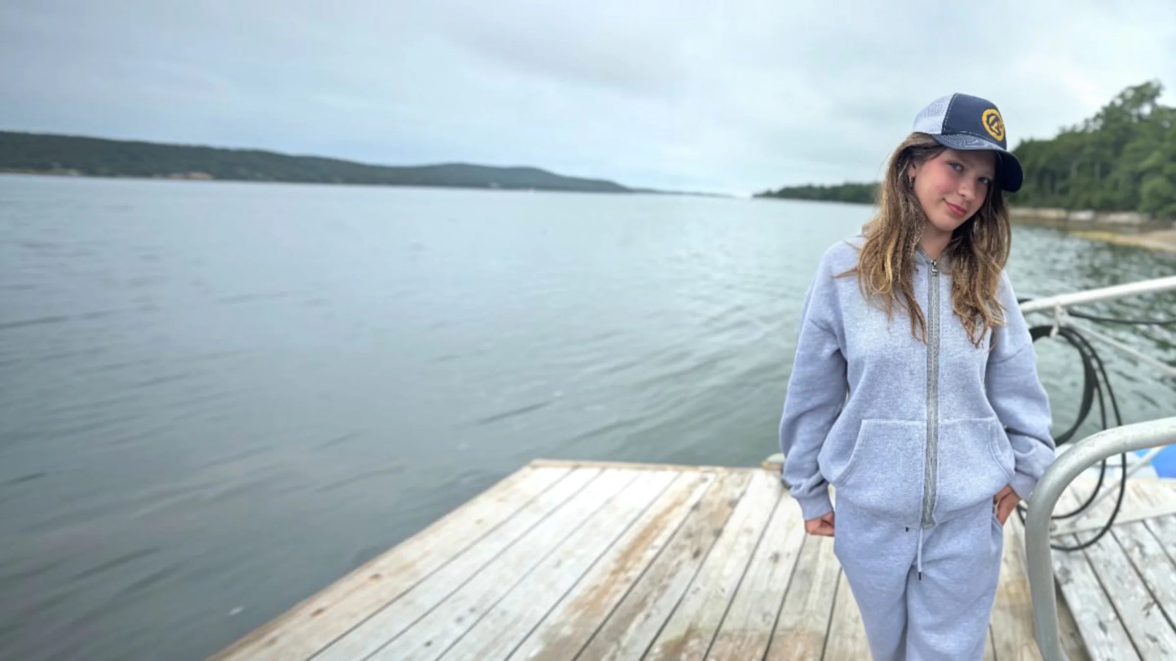 A girl in the gray FREEDOM Hoodie and Jogger on a lake dock