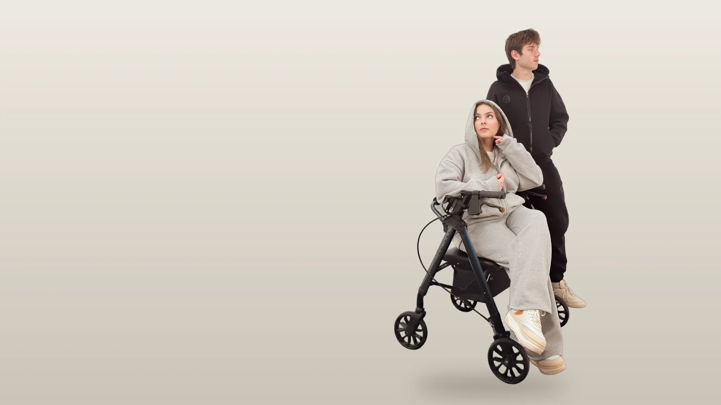 A woman in the gray FREEDOM set seated on a rolling walker, a young man beside her in the black set