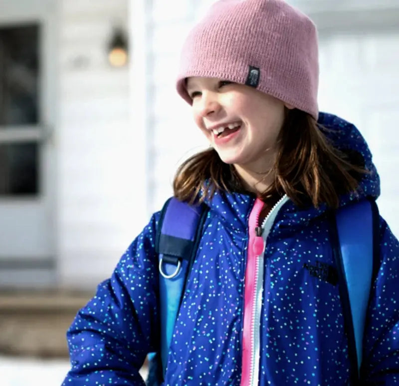 A smiling girl in a pink hat and a zipped winter coat