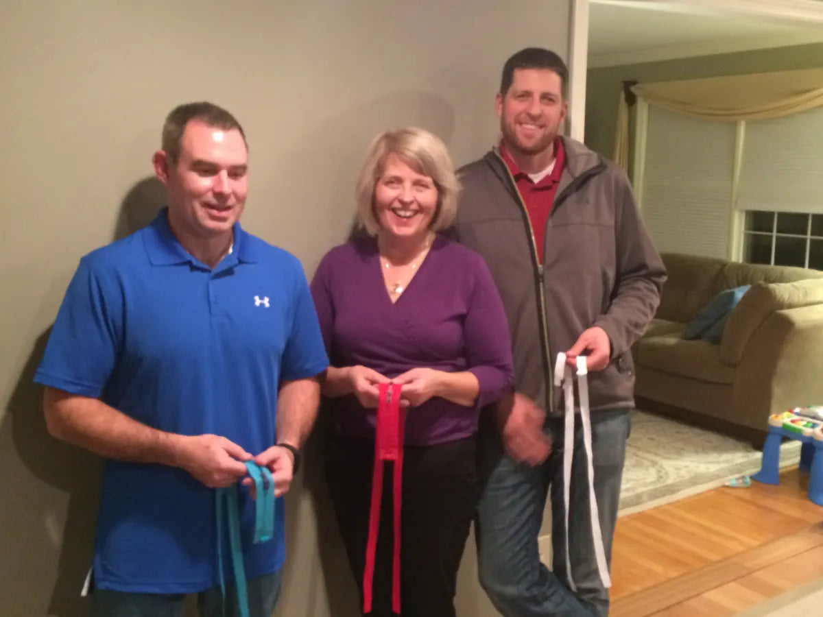 The team standing in a living room holding colored MagZip zippers, photographed for a Democrat and Chronicle story